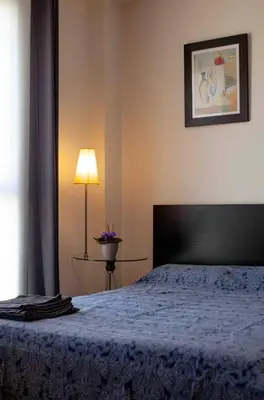 a bedroom with a bed with a blue blanket and a lamp at A studio-apartment in a newly built house.WIFI in Valencia
