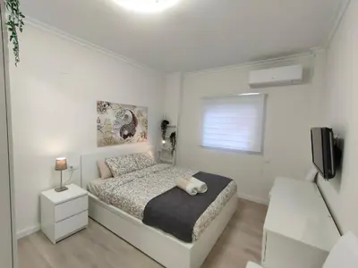 a white bedroom with a bed and a television at Non Stress Turia in Valencia