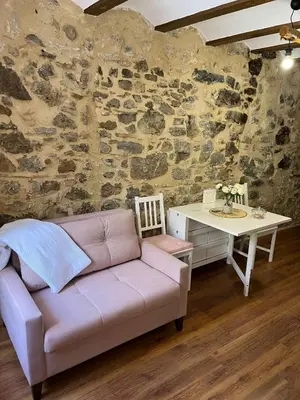 a couch and a desk in a room with a stone wall at Apartamento Rural Piedra in Jérica