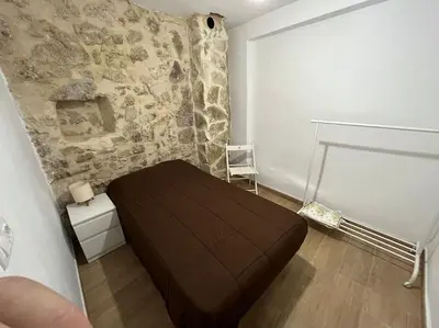 a bedroom with a brown bed in a room with a stone wall at Apto. Rural Cielo. Al lado Torre in Jérica