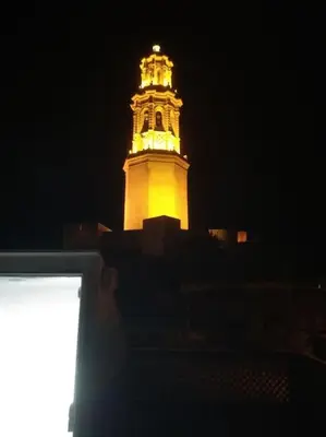 a tall clock tower lit up at night at Apto. Rural Cielo. Al lado Torre in Jérica