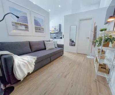 a living room with a gray couch and a wooden floor at Apartamento nuevo cerca de la playa y céntrico in Valencia