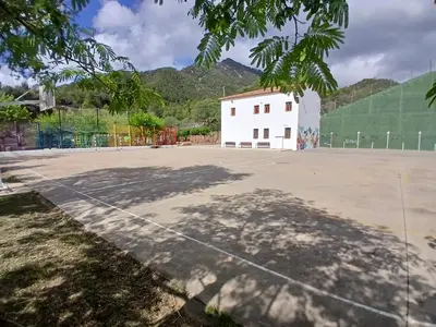 a basketball court in front of a white building at L'Amagatall in Ahín