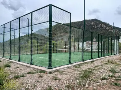 a batting cage on a field with a mountain in the background at L'Amagatall in Ahín