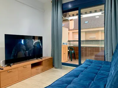 a living room with a tv and a blue couch at Experience Valencia Bnb - Rincon del Mar - Apartamento Maravilloso a Canet Playa 100 mt in Canet de Berenguer