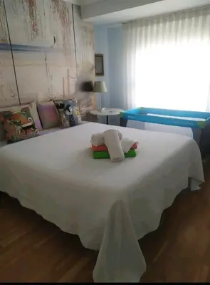 a bedroom with a white bed with two towels on it at Precioso apartamento a 7 minutos en tren al centro de Valencia in Benetúser