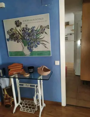 a blue wall with a picture of flowers in a vase at Precioso apartamento a 7 minutos en tren al centro de Valencia in Benetúser
