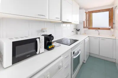 a white kitchen with a microwave and a sink at Travel Habitat Port Saplaya con vistas al Mar in Port Saplaya