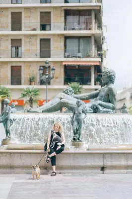 a woman sitting in front of a fountain with a dog at Habitación céntrica de Lujo Gv 3 in Valencia