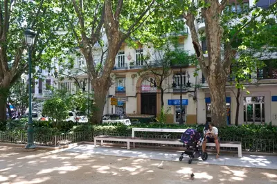 a man sitting on a park bench with a baby in a stroller at Habitación céntrica de Lujo Gv 5 in Valencia