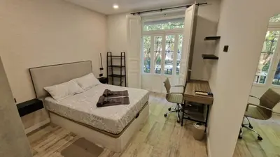 a bedroom with a bed and a desk and windows at Habitación céntrica de Lujo Gv 2 in Valencia