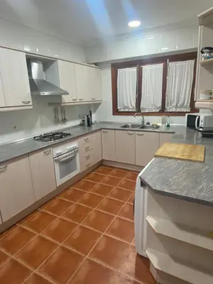 a kitchen with white cabinets and a tile floor at La casa de bega de mar in Sueca
