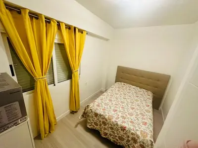 a small bedroom with yellow curtains and a bed at Piso Lorena Playa 1min walk in Puerto de Sagunto