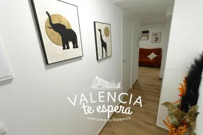 a hallway with paintings on a white wall with a room at ¡A disfrutar de Valencia! in Valencia