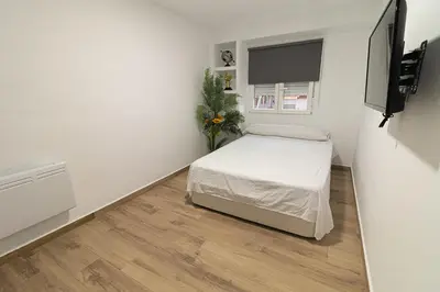 a small white room with a bed and a television at ¡A disfrutar de Valencia! in Valencia
