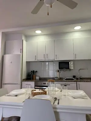 a kitchen with white cabinets and white tables and chairs at APARTAMENTO PLANTA BAJA CANET DE BERENGUER in Canet de Berenguer