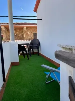 a balcony with green grass and two chairs and a table at Casa mediterránea junto al mar. in Chilches