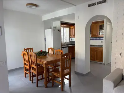 a kitchen and dining room with a wooden table and chairs at Casa mediterránea junto al mar. in Chilches