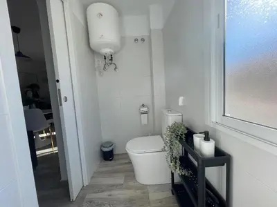 a white bathroom with a toilet and a window at Apartamento El Castell in Alaquas