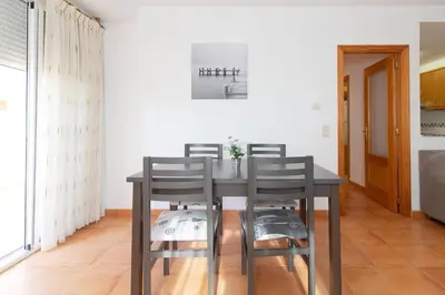 a dining room with a table and four chairs at Global Vacacional, Práctico apartamento con piscina en la playa de Canet in Canet de Berenguer