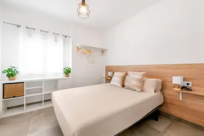 a white bedroom with a large bed and a window at Bombonera 2 Jacuzzi in Catadau