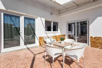 a patio with white chairs and a wooden table at Bombonera 2 Jacuzzi in Catadau