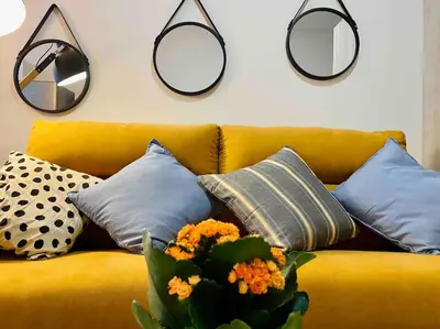 a yellow couch with pillows and mirrors on the wall at Studio chic avec terrasse, lumineux et calme 1 in Valencia
