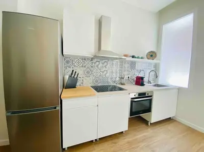 a kitchen with a stainless steel refrigerator and white cabinets at Studio chic avec terrasse, lumineux et calme 1 in Valencia