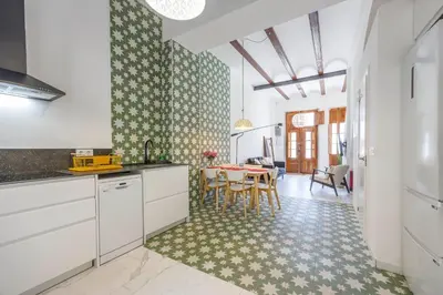 a kitchen with white cabinets and a table with chairs at Artisan Haven: El Cabanyal Oasis in Valencia