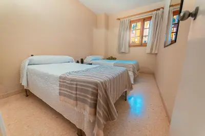 two twin beds in a room with a window at Apartamento familiar Port-Saplaya in Port Saplaya