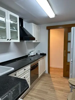 a kitchen with white cabinets and black counter tops at Frente al puerto y junto a la playa del Arenal in Burriana