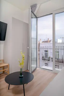a living room with a table and a large window at Limehome Valencia Carrer de Sant Jacint in Valencia
