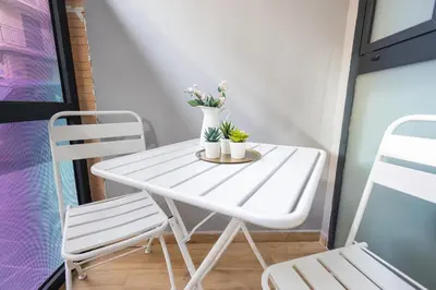 a white table and chairs on a balcony with flowers at FLORIT FLATS - The Joaquin Sorolla Station Apartments in Valencia