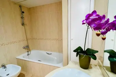 a bathroom with a sink and a vase with purple flowers at Apto con vistas a la playa de La Patacona in Valencia