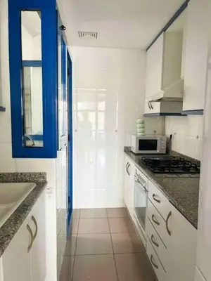 a kitchen with white cabinets and a blue door at Apto con vistas a la playa de La Patacona in Valencia