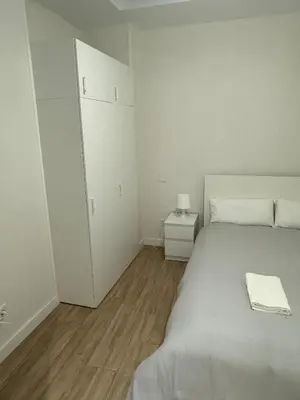 a white bedroom with a bed and a night stand at Mercado CENTRAL on 1th FLOOR in Valencia