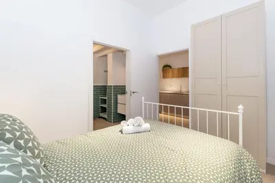 a white bedroom with a bed and a kitchen at GuestReady - Valencia's Vibrant Malvarrosa in Valencia