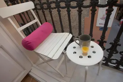 a white chair with a purple pillow and a glass of orange juice at SingularStays Roteros in Valencia