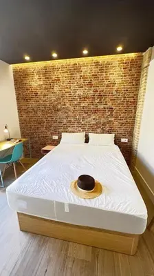 a bedroom with a large bed with a brick wall at Beach Valencia Rooms Late Checkout 14 h free Netflix Tv in Valencia