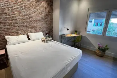 a large white bed in a room with a brick wall at Beach Valencia Rooms Late Checkout 14 h free Netflix Tv in Valencia