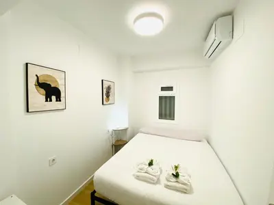 a white bedroom with a bed and two towels at BatFlats - RUZAFA in Valencia