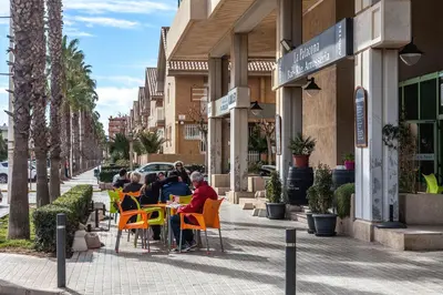 a group of people sitting at tables on a sidewalk at Valencia Flat Rental Patacona Beach in Valencia