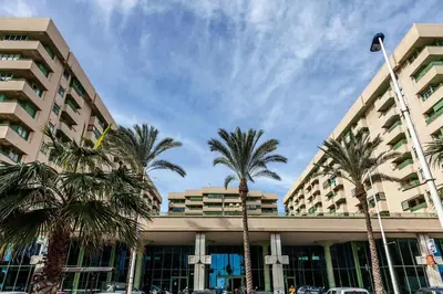 a building with palm trees in front of it at Valencia Flat Rental Patacona Beach in Valencia