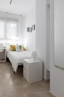 a white bedroom with a bed and a table at DormForYou Jose Maria Haro in Valencia