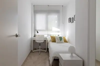 a white bedroom with a bed and a desk at DormForYou Jose Maria Haro in Valencia
