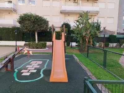 a playground with an orange slide in front of a building at Canet estival in Canet de Berenguer