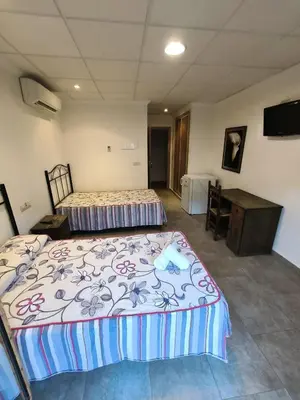 a bedroom with two beds and a desk and a television at Ca' La Conchin in Cortez de Pallas