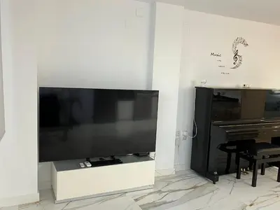 a large flat screen tv on a wall next to a piano at MAGNÍFICO ADOSADO CERCA DEL MAR in Canet de Berenguer