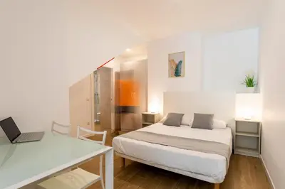 a bedroom with a bed and a desk with a laptop at SOROLLA APARTMENTS CENTRAL Station in Valencia