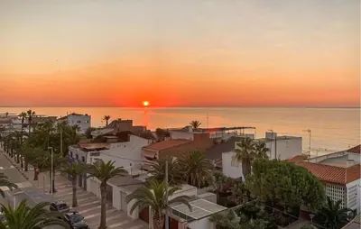 a sunset over a city with palm trees and the ocean at 2 Bedroom Awesome Apartment In Moncofa in Moncófar